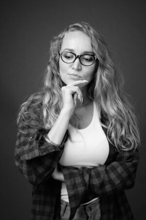 Young beautiful woman with long wavy blond hair against gray backgroundの写真素材