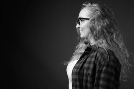 Young beautiful woman with long wavy blond hair against gray backgroundの写真素材