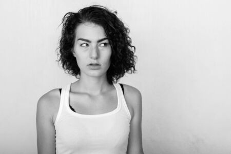 Close up of beautiful teenage girl thinking while looking at distance against green painted wallの写真素材