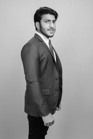Young handsome Indian businessman against gray backgroundの写真素材