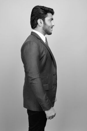 Young handsome Indian businessman against gray backgroundの写真素材