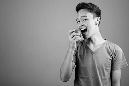 Young handsome Indian man against gray background