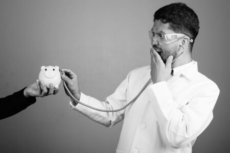 Bearded Persian man doctor wearing protective glasses against gray backgroundの写真素材