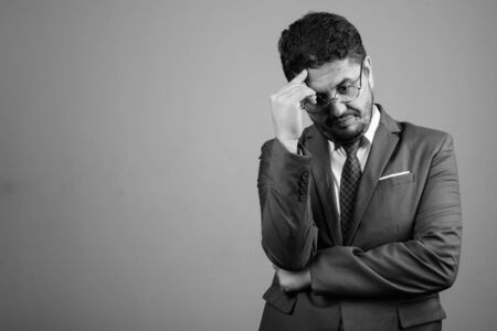 Bearded Persian businessman wearing suit against gray backgroundの写真素材