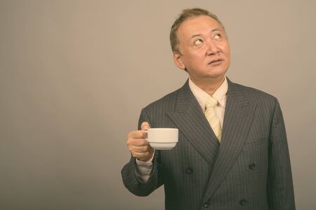 Portrait of mature Asian businessman having coffee breakの写真素材