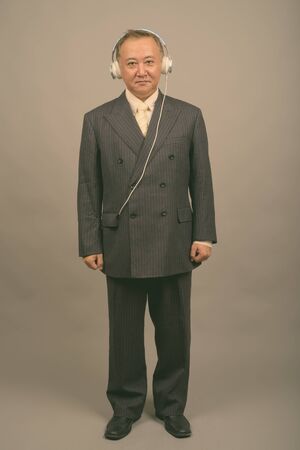 Portrait of mature Asian businessman listening to musicの写真素材