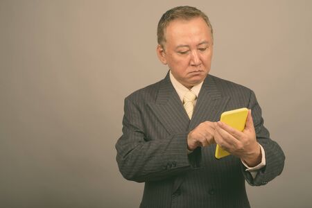 Portrait of mature Asian businessman using phone