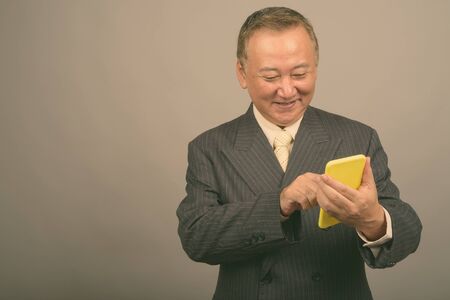 Portrait of mature Asian businessman using phone