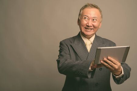 Portrait of mature Asian businessman using digital tablet