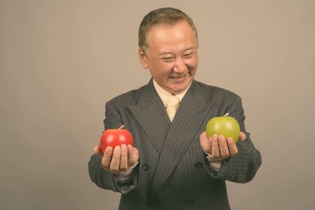 Portrait of mature Asian businessman with appleの写真素材