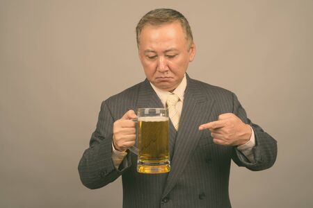 Portrait of mature Asian businessman with glass of beer