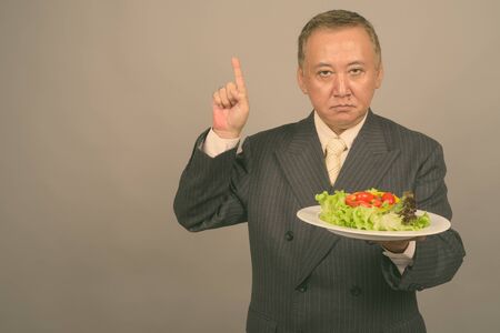 Portrait of mature Asian businessman with plate of saladの写真素材