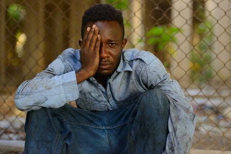 Young homeless African man looking depressed in the streetsの写真素材