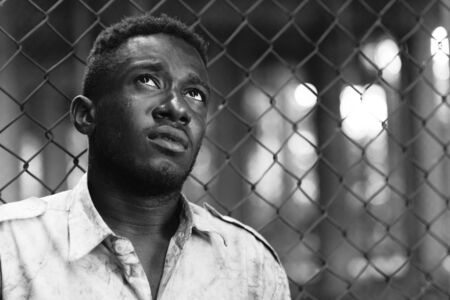 Face of young homeless African man looking up in black and whiteの写真素材