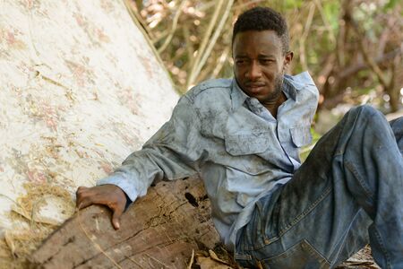 Sad young homeless African man sitting in the streets