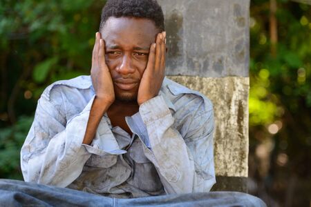 Young homeless African man looking depressed on the bridgeの写真素材