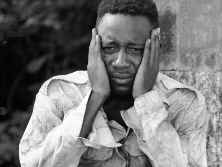 Face of young homeless African man looking depressed in black and whiteの写真素材