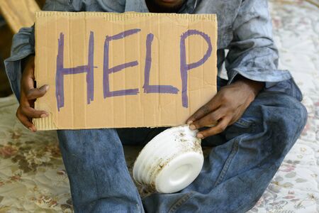 Young homeless African man with cardboard sign asking for help