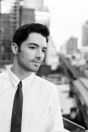 Portrait of young handsome businessman against view of the city