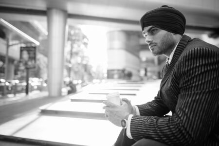 Young handsome Indian Sikh businessman wearing turban in the city
