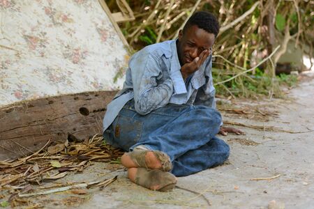 Sad young homeless African man crying in the streets