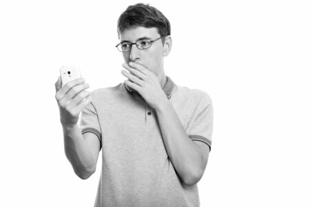 Studio shot of man holding mobile phone looking shockedの写真素材