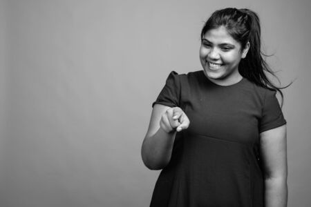 Young beautiful overweight Indian woman against gray backgroundの写真素材