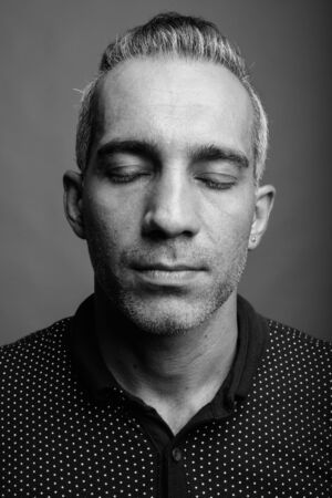 Handsome Persian man with gray hair against gray background