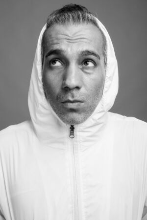 Handsome Persian man with gray hair against gray backgroundの写真素材