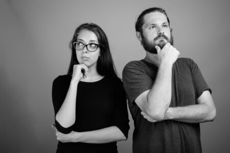 Young bearded man and young beautiful woman together against gray backgroundの写真素材