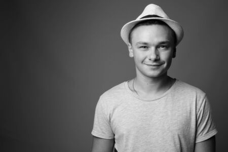 Portrait of young handsome tourist man against gray background