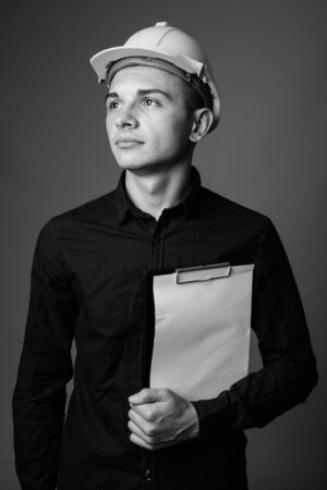 Young handsome businessman as engineer against gray backgroundの写真素材