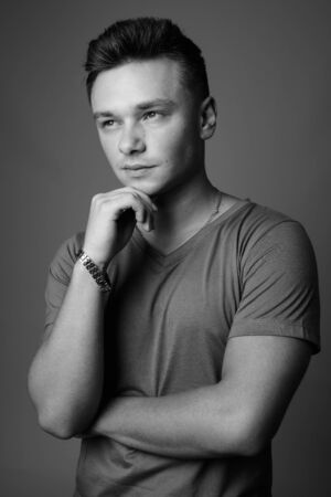 Portrait of young handsome man against gray backgroundの写真素材