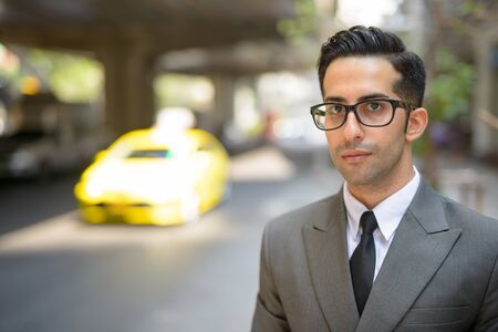 Face of young handsome Persian businessman thinking in the city streets outdoors