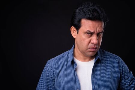 Mature handsome Indian man against black background