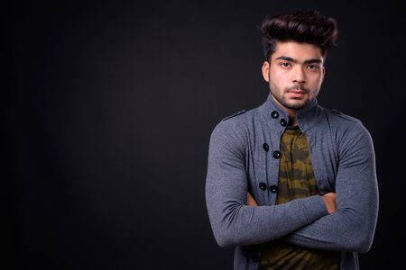 Young handsome Indian man against black background