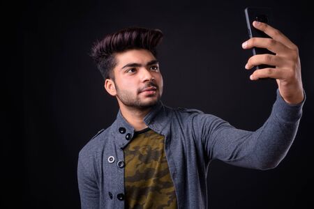 Young handsome Indian man against black background