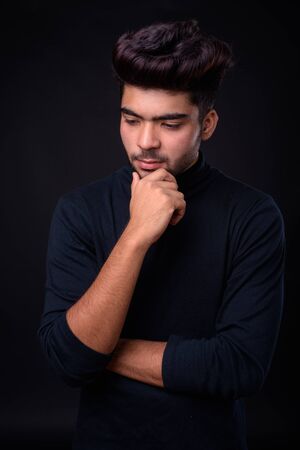 Young handsome Indian man against black background