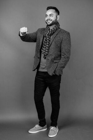 Young bearded Indian businessman against gray backgroundの写真素材
