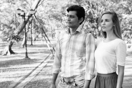 Multi ethnic couple thinking while looking at distance with woman leaning on shoulder at the pathway...