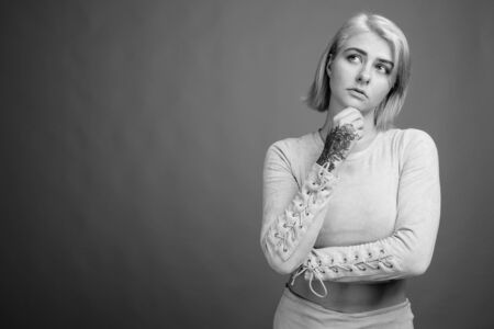 Young beautiful rebel woman with short hair against gray backgroundの写真素材