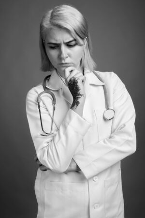 Young beautiful woman doctor with short hair against gray backgroundの写真素材