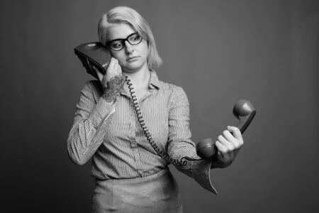 Young beautiful businesswoman with short hair against gray backgroundの写真素材