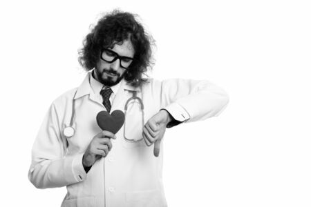 Sad man doctor holding red heart while giving thumb downの写真素材