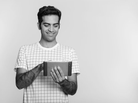 Young happy Persian man using digital tablet