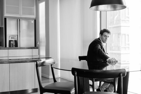 Young handsome businessman sitting in the dining room near the kitchen