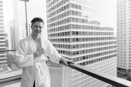 Young handsome man enjoying the view of the city from the balconyの写真素材