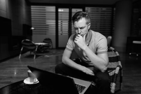 Young handsome man using laptop in the living roomの写真素材