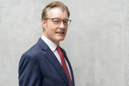 Closeup profile view of happy mature businessman smiling and looking at camera outdoors