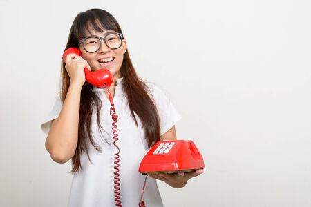Portrait of happy young Asian nerd woman using old telephoneの写真素材